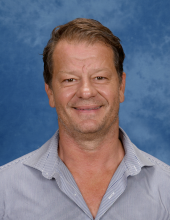 A man in a white shirt smiles at the camera
