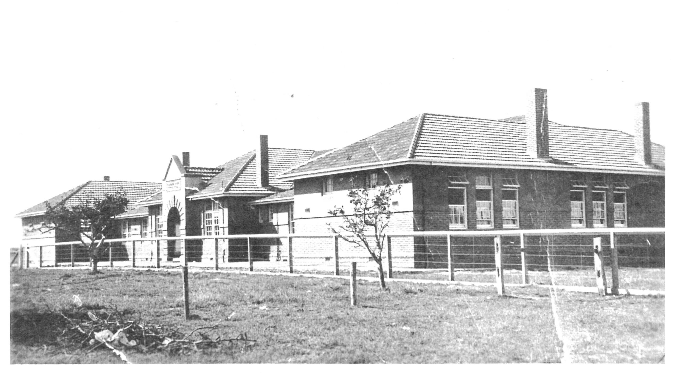 A black and white image of a single storey school building